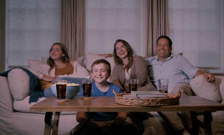 Family sitting on the couch watching a movie.