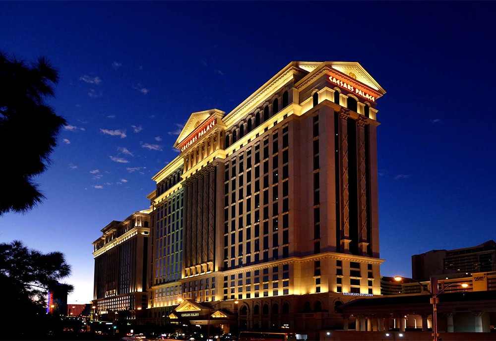 Caesar's Palace front facade in Las Vegas, NV shown lit up as night falls.