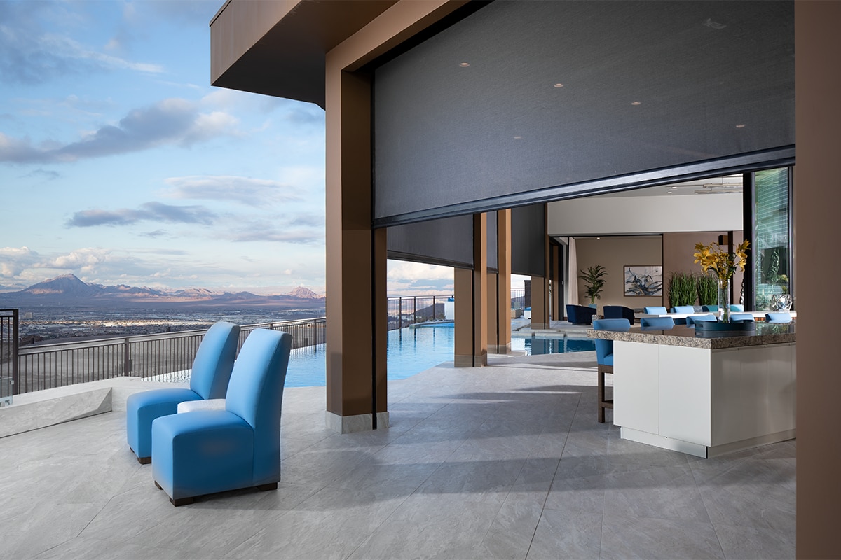 Outdoor living space with a sitting area and pool with outdoor shades rolling up to reveal an outdoor dining area.
