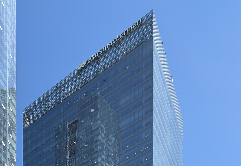 Looking up toward the top of the Southcore Financial Centre building with the sky in the background and the words 'Marsh McLennan' on one side of the building.