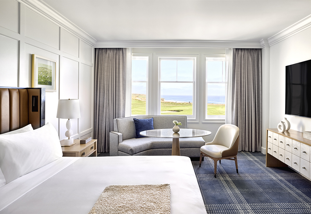 The interior of a guest bedroom looking out of a balcony with the curtains wide open.