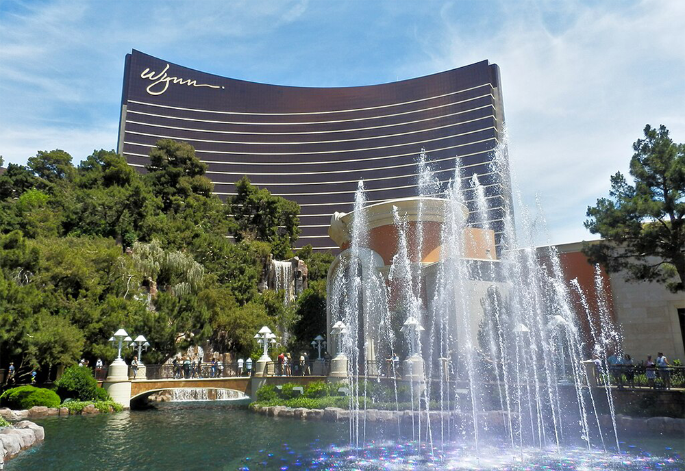 Wynn hotel in the background with a fountain, pond and bridge in the foreground.