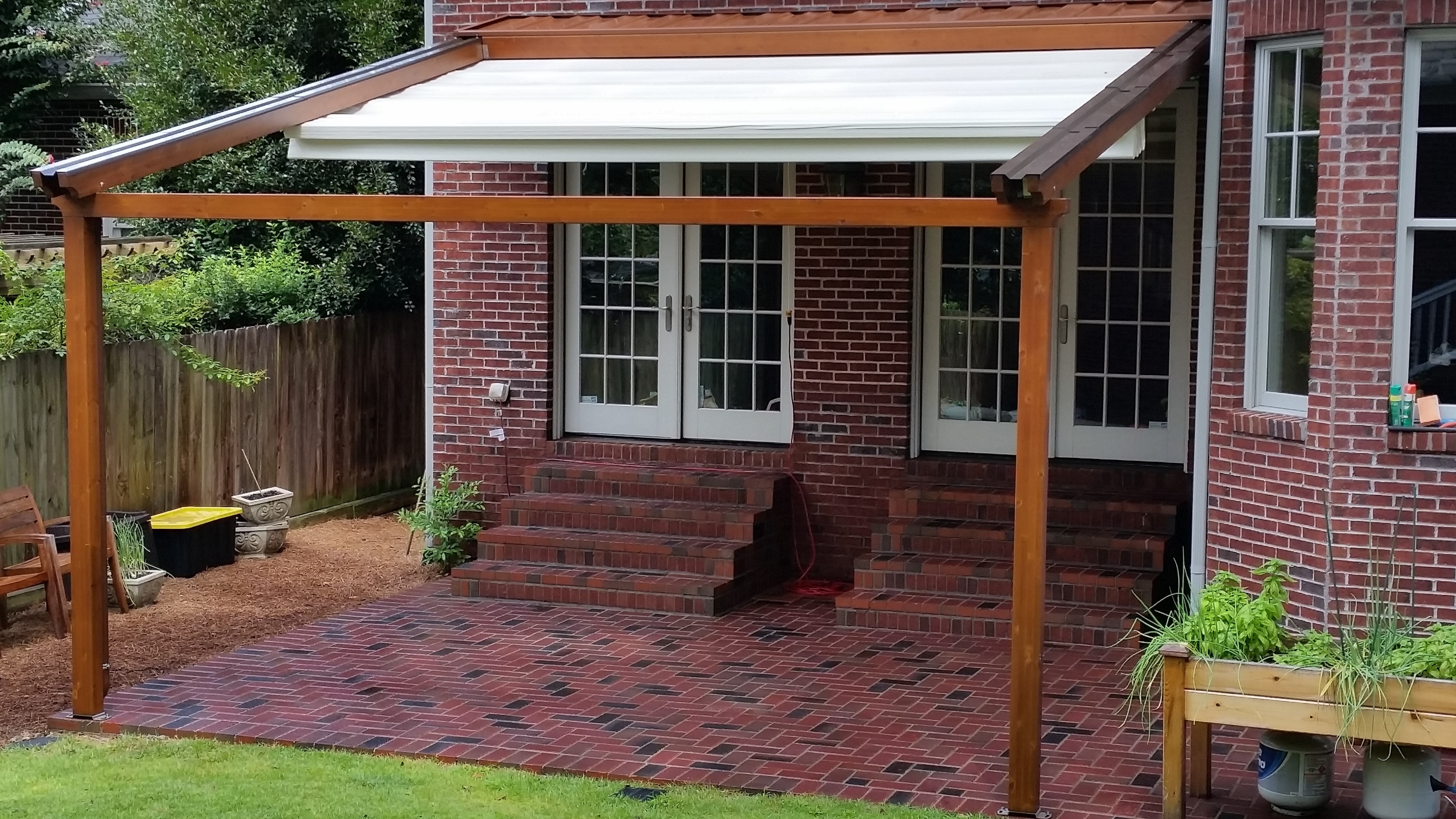 Brick house with retractable awning half extended in backyard