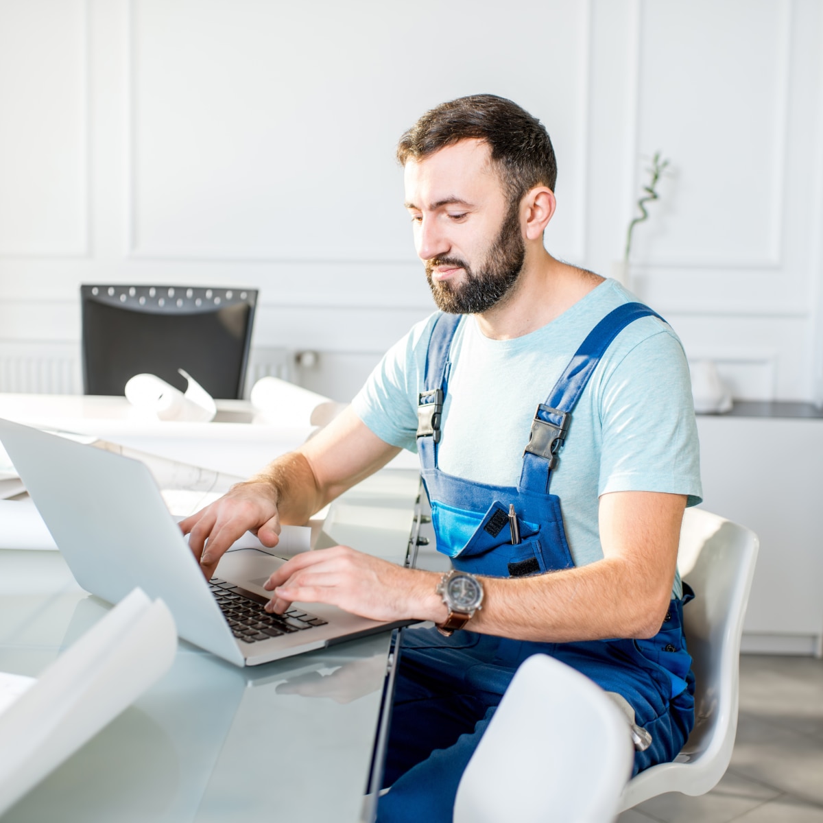 Dealer sitting at a dining room table at a jobsite on his laptop.