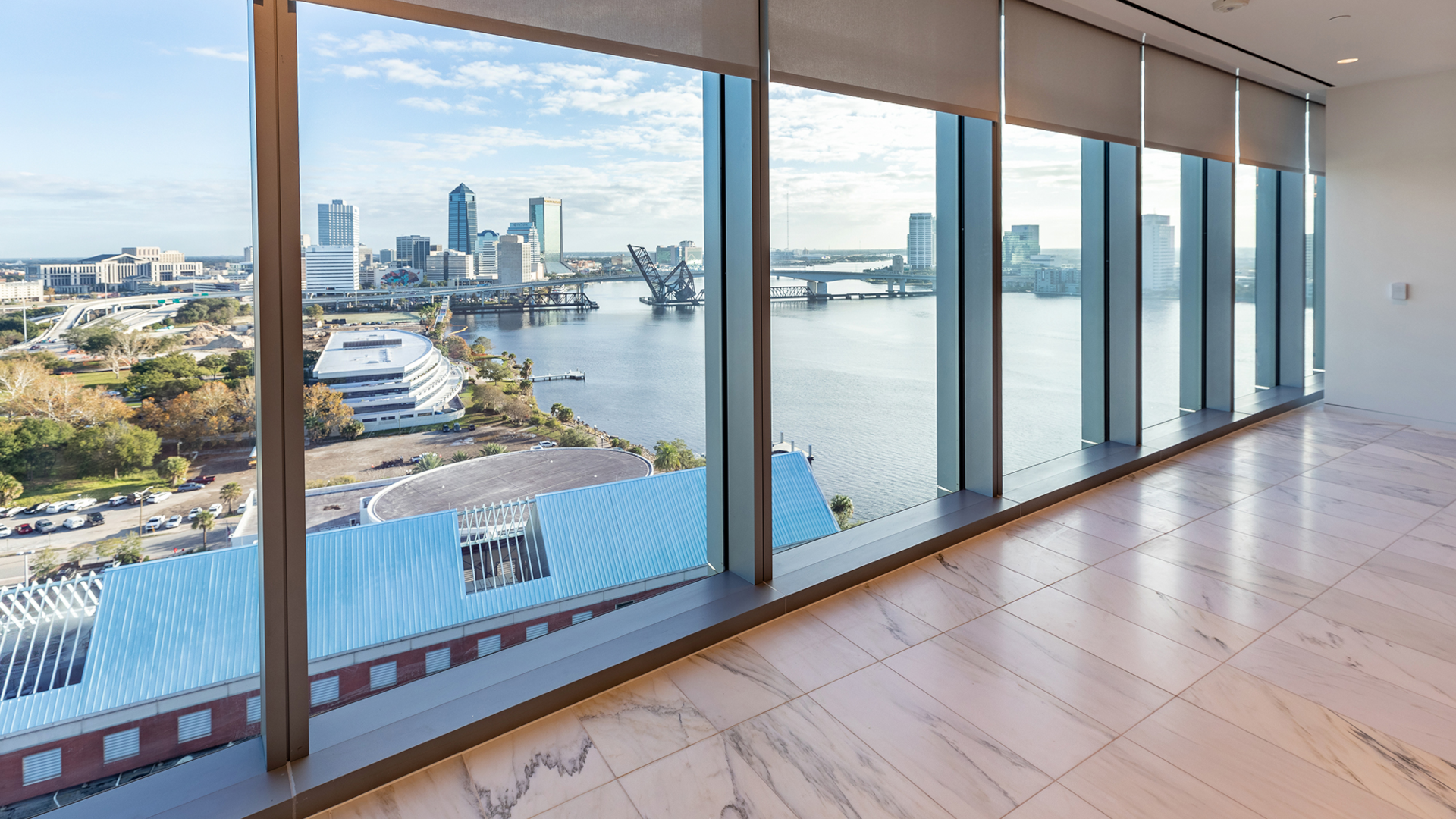 Floor to ceiling windows letting in sunlight, overlooking the harbor.