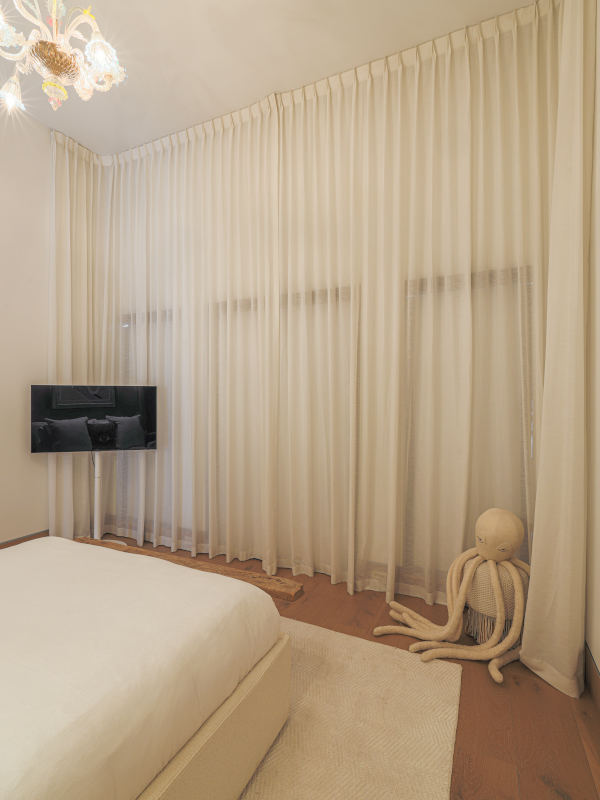 Modern bedroom with both shades and curtains closed and the lights on.